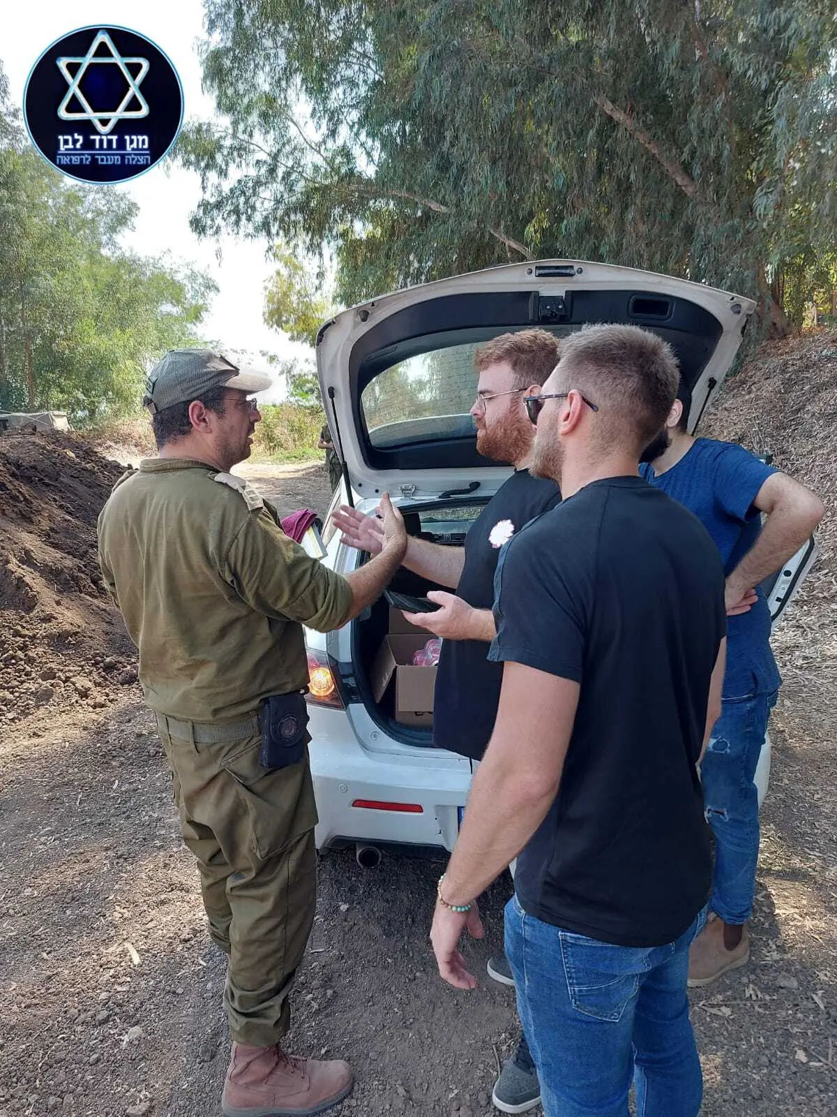 מתנדבים מחלקים ארגזים לחיילים ליד רכב