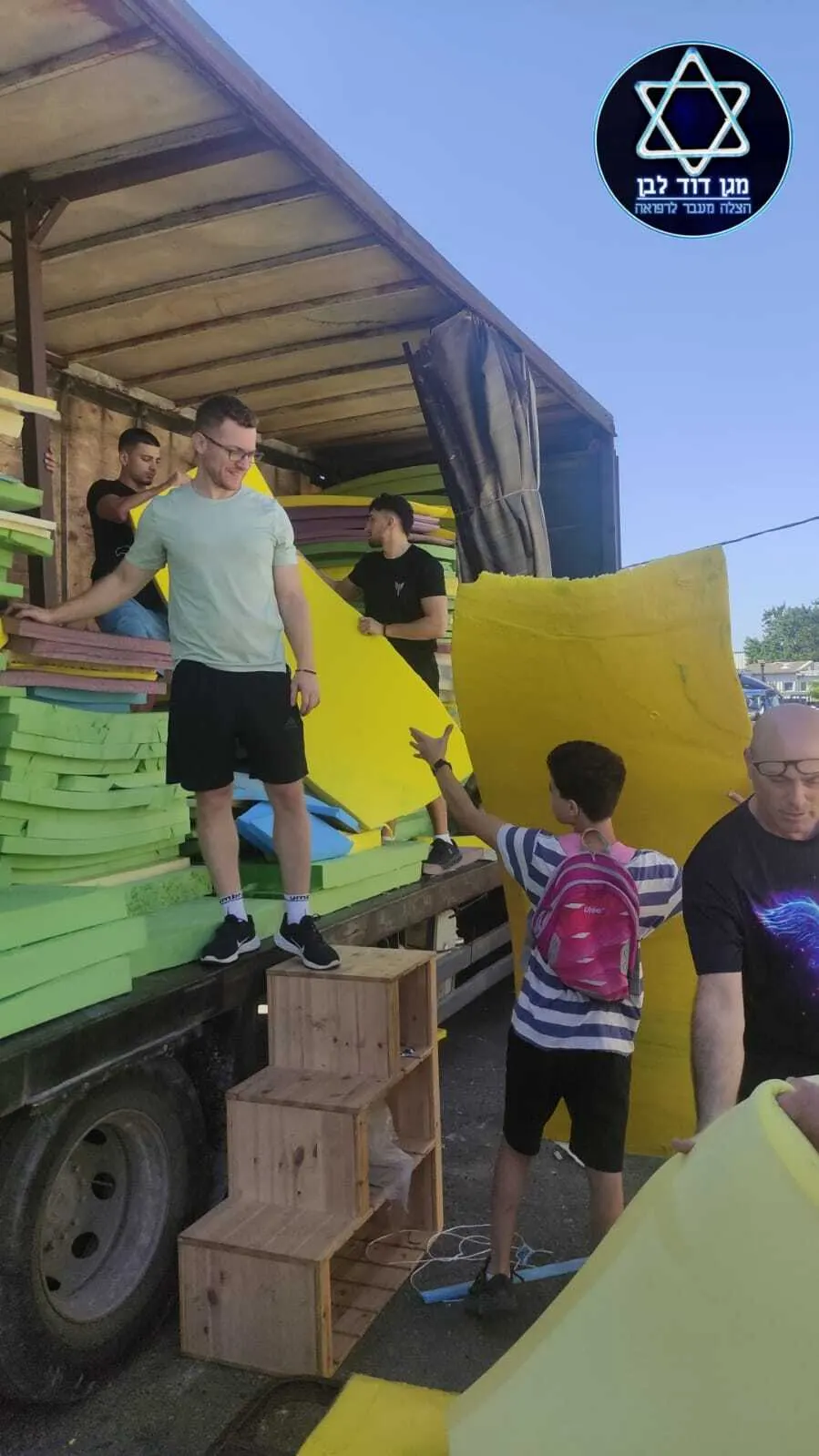 מתנדבים פורקים מזרנים ממשאית